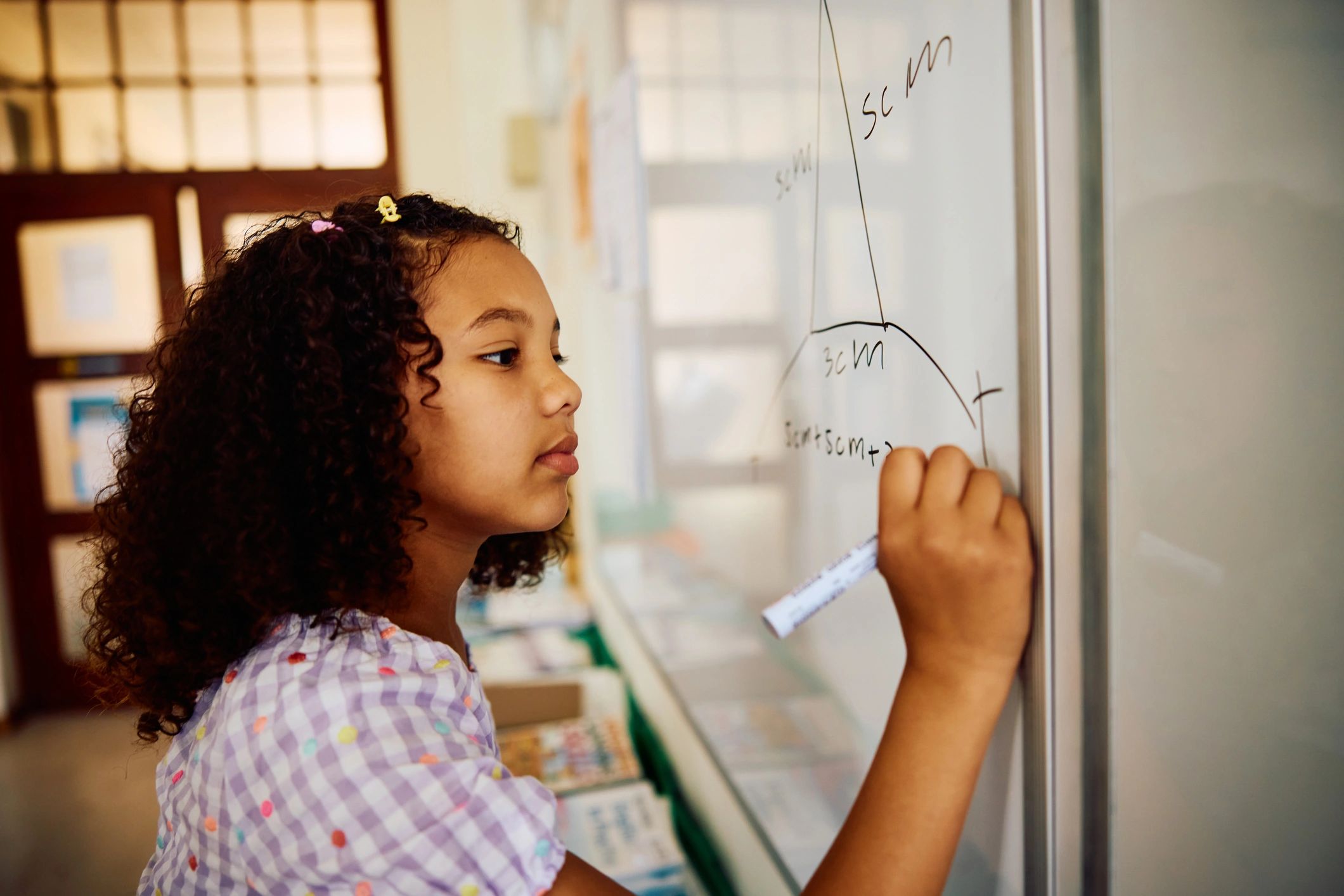 Student writing on a whiteboard in a classroom